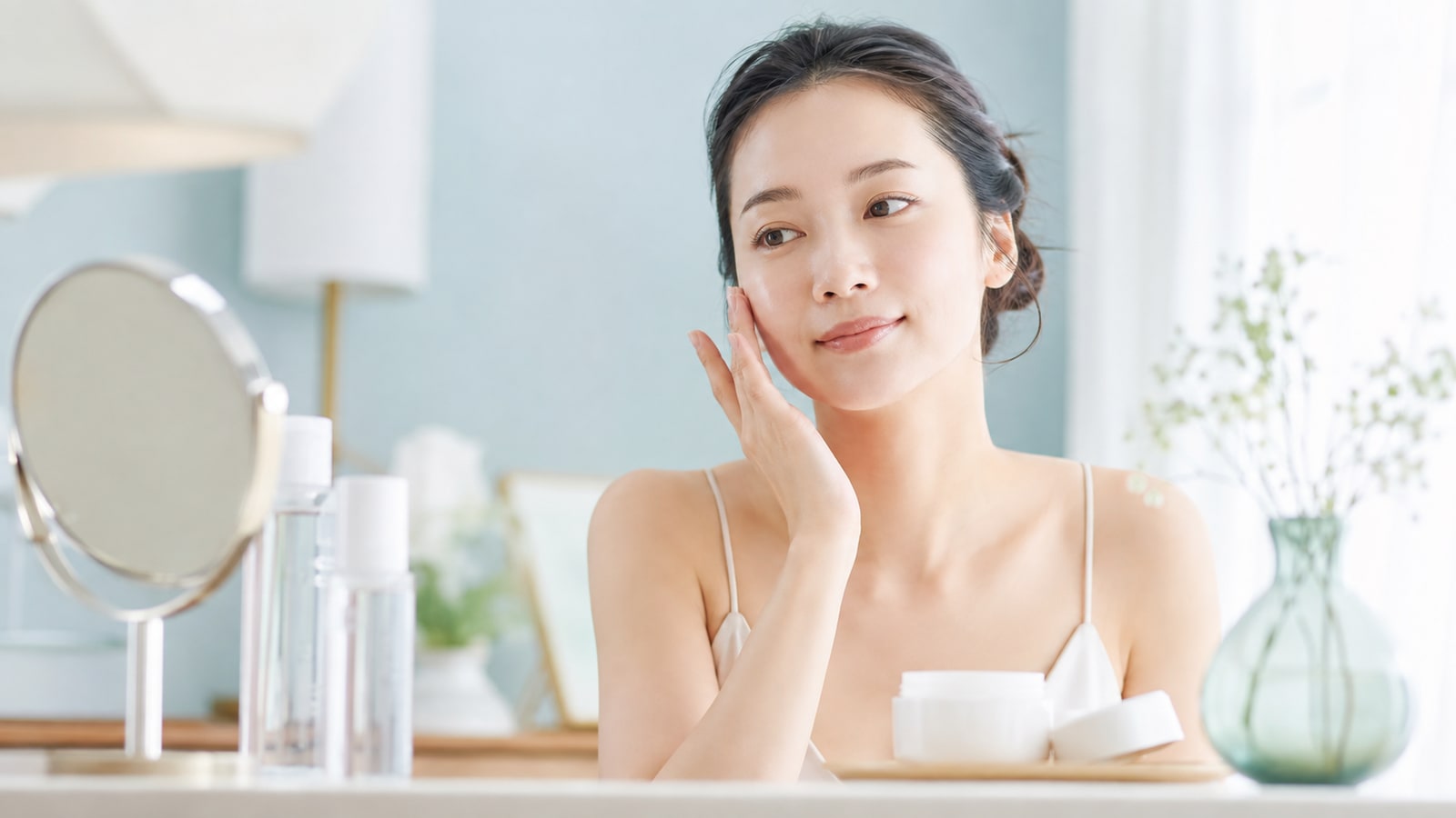 洗顔後に化粧水をなじませてからクリームを塗る女性