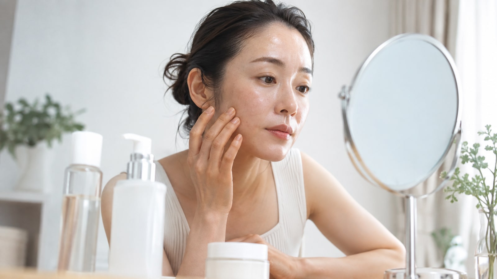 乾燥やベタつきなど肌状態を鏡で確認する女性
