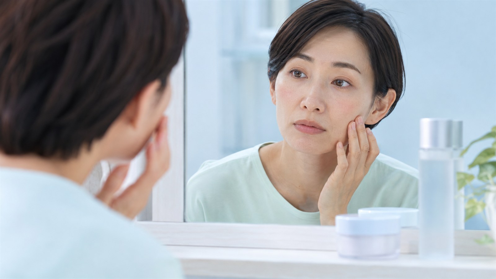 鏡で頬の乾燥や刺激を確認する女性